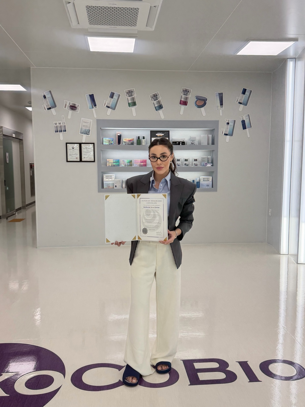 Brenda holding her ExoCoBio certificate at the company headquarters
